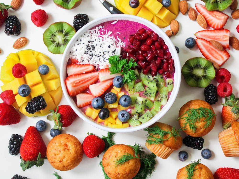 A variety of colored fruits and vegetables in and around the bowl